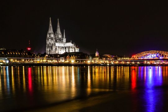 Hier ist der Kölner Dom bei Nacht zu sehen, im Vordergrund der Rhein