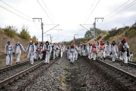 Dutzende weiß gekleidete Menschen laufen auf den Gleisen der Hambachbahn.