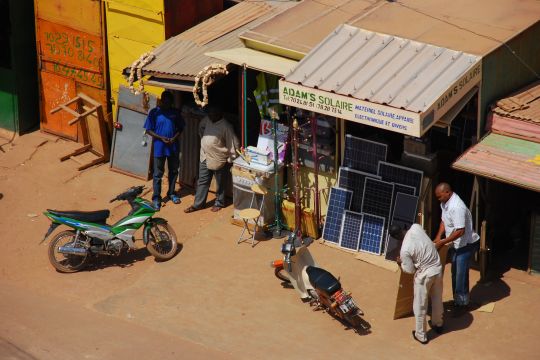 Kunden stehen vor einem Solar-Laden in einem Holzhaus.