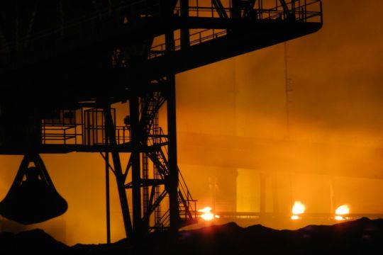 Im Stahlwerk: industrielles Gerüst, rötliches Licht.