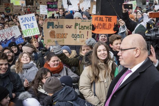 Demonstrantinnen stehen Peter Altmaier gegenüber und fordern auf Schildern Klimaschutz.