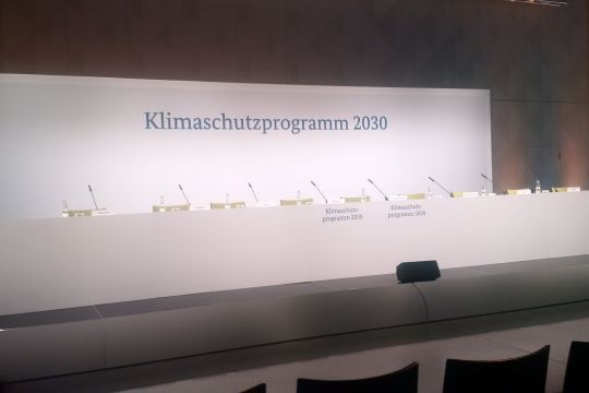 Leere Stühle auf einem Podium mit der Aufschrift "Klimaschutzprogramm 2030".
