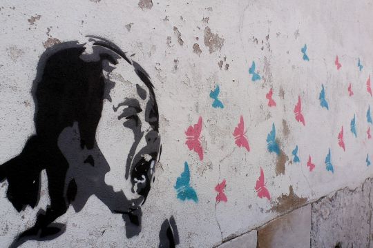 Graffito: Mädchen schreit bunte Schmetterlinge