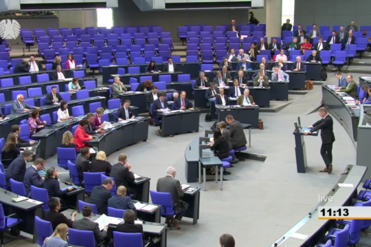 Ein Mann redet vor dem zu drei Vierteln leeren Bundestag.