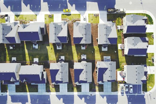 Blaue Dächer einer Einfamilienhaussiedlung von oben betrachtet.