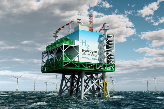 Plattform steht im Meer, darauf ein hausgroßer Kasten mit der Aufschrift "H₂ Hydrogen Offshore Energy".in einiger Entfernung stehen Windräder.
