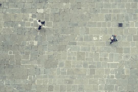 Zwei Fußgänger auf einem leeren Platz