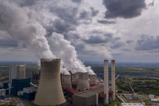 Dampfende Kühltürme und rauchende Schornsteine eines RWE-Kohlekraftwerks.