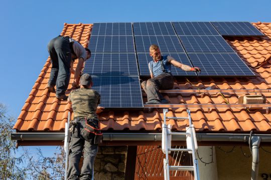 In Ochojno südlich von Krakau montieren drei Männer eine Solaranlage auf ein Hausdach.