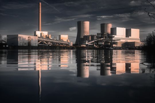 Ein Kohlekraftwerk spiegelt sich abends in einem Fluss