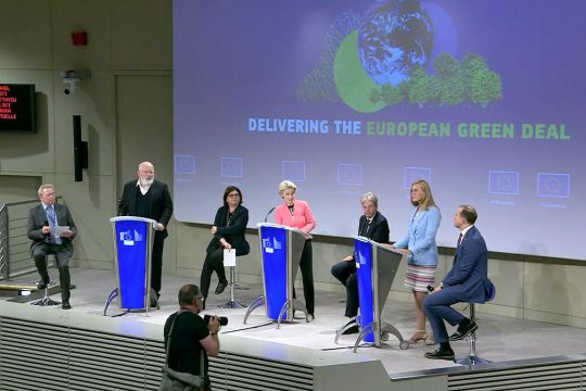 Mehrere EU-Kommissionsmitglieder, darunter Ursula von der Leyen und Frans Timmermans, stehen an Pulten, hinter ihnen der projizierte Schriftzug auf Englisch: Wir liefern den europäischen Green Deal.