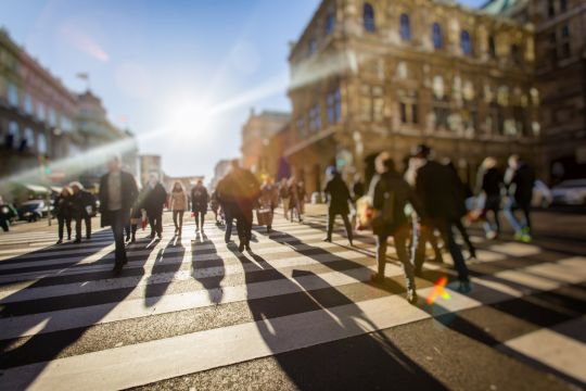 Menschen laufen auf einer belebten Großstadtstraße .