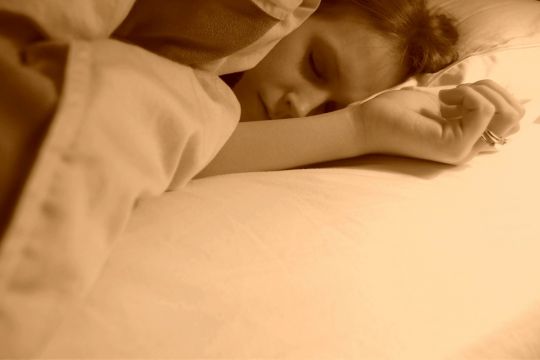 Schlafende Frau in einem Bett mit weißem Bettzeug.
