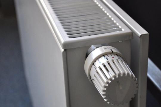 Der Thermostat an einem weißen Flachheizkörper steht zwischen Stufe drei und vier.