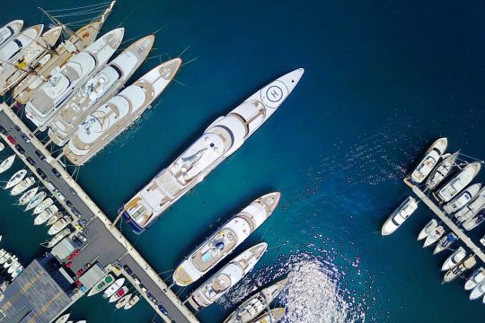 Luftaufnahme: Yachthafen von Monaco in der Draufsicht mit einigen großen Yachten und einer Megayacht.
