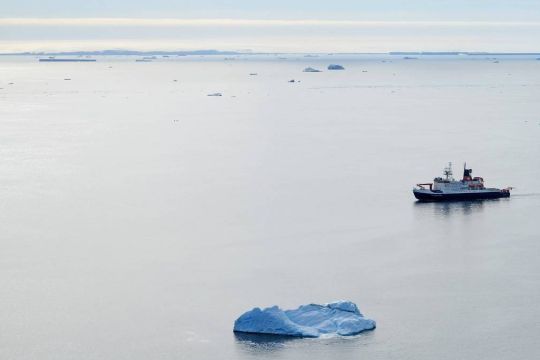 Ein Schiff fährt auf dem Südlichen Ozean zwischen sehr vereinzelten kleinen Eisschollen.