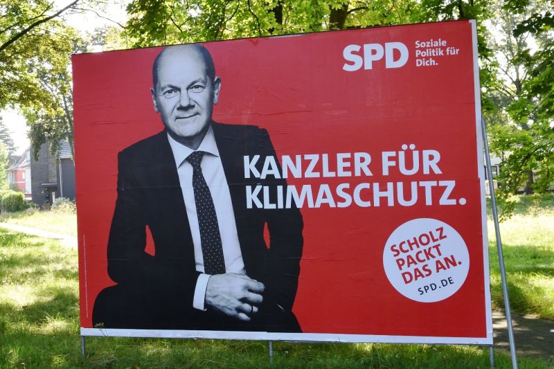 Ein jung wirkender Olaf Scholz in Schwarz-Weiß auf einem roten Wahlplakat, darauf steht in Weiß: Kanzler für Klimaschutz – Scholz packt das an.