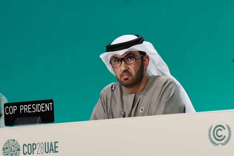 Sultan Al Jaber sitzt auf dem Podium der COP 28 und schaut ernst.
