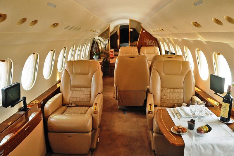 Innenraum eines Privatflugzeugs mit Ledersesseln und einem gedeckten Tisch.