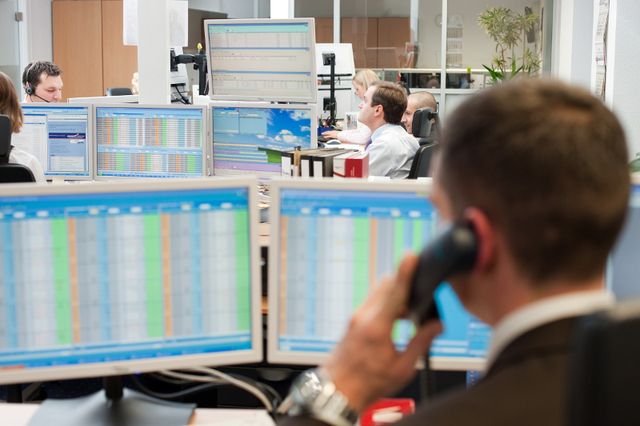 An der Emissionshandelsbörse in Leipzig sitzt ein Mann am Computer und spricht in einen Telefonhörer.