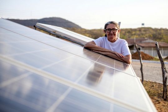 Eine Frau lehnt sich auf eine Photovoltaik-Anlage