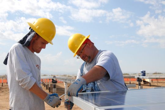 Zwei Arbeiter montieren ein Solarmodul.