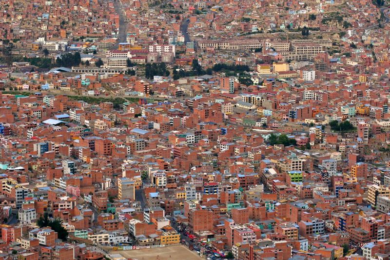 Luftbild der Stadt El Alto in Bolivien, es sind viele ziegelrote und einige weiße mehrstöckige Häuser zu sehen.