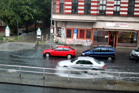 Ein Auto fährt durch eine überflutete Straße in Berlin.