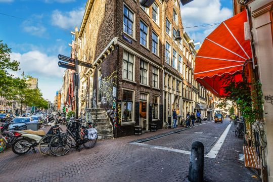 Hier ist eine schöne Seiteseite von Amsterdam zu sehen, mit wenig Autos und vielen Fahrrädern