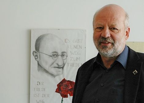 Hans-Josef Fell vor einem gezeichneten Porträt von Mahatma Gandhi.