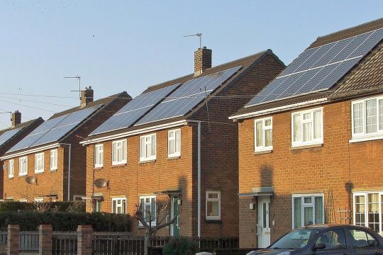 Zweistöckige Backstein-Reihenhäuser mit Solarpaneelen auf dem gesamten Dach.