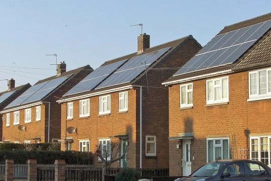 Zweistöckige Backstein-Reihenhäuser mit Solarpaneelen auf dem gesamten Dach.