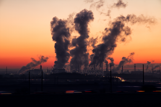 Industrieanlagen mit rauchenden Schloten in der Abenddämmerung