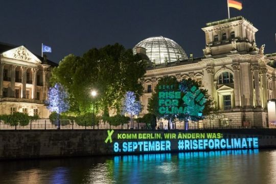 Auf die Ufermauer am Reichstagsgebäude ist nachts ein Slogan projiziert: