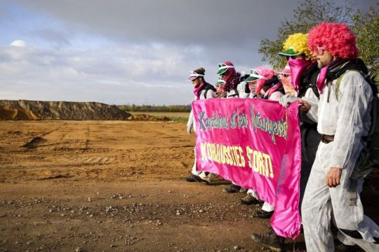 Weiß gekleidete Demonstranten von "Ende Gelände" ziehen mit Transparent zum Tagebau Hambach.