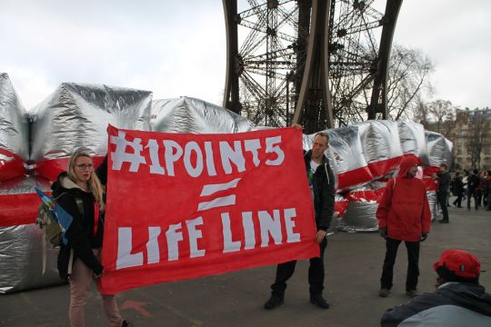 Aktivisten unter dem Eiffelturm halten Transparent "1Point5 = Life Line"
