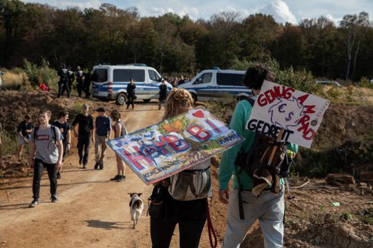 Zwei Menschen mit Plakaten auf dem Weg zur Demonstration am Hambacher Forst.