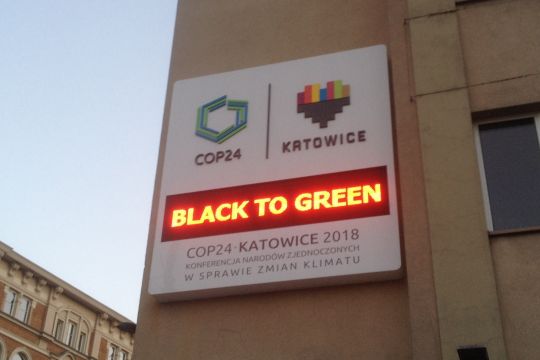 Tafel an einem Haus in Katowice mit dem Zeichen des Klimagipfels 2018 und der Leuchtschrift