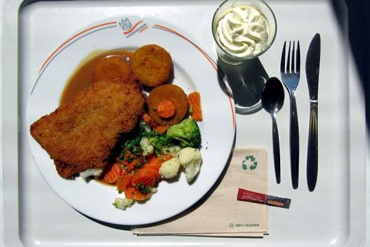 Ein Teller mit Schnitzel und Gemüse und ein Nachtisch stehen auf einem Tablett
