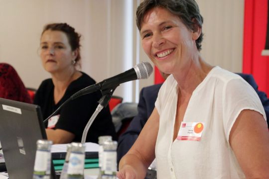 Kathy Ziegler lächeln bei einer Konferenz auf dem Podium am Mikrofon.