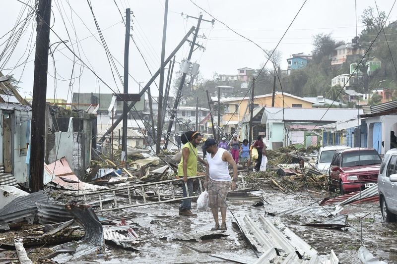 Einige Leute versuchen sich einen Weg durch die Trümmer auf einer Straße auf Dominica zu bahnen.