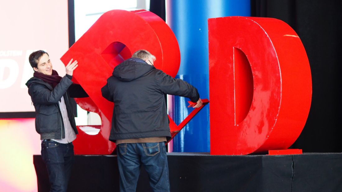 Zwei Arbeiter bauen große Buchstaben S, P und D für einen SPD-Parteitag auf.