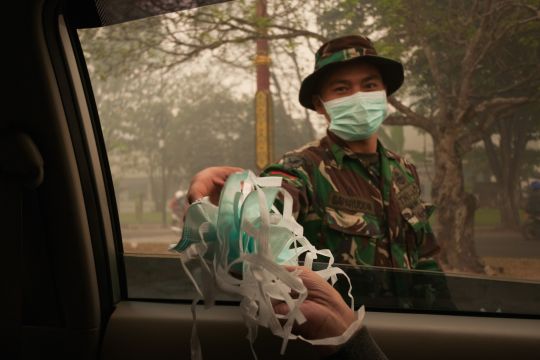 Ein Soldat reicht Atemschutzmasken an die Autofahrer, die durch die Stadt Palangkaraya, Central Kalimantan, fahren.