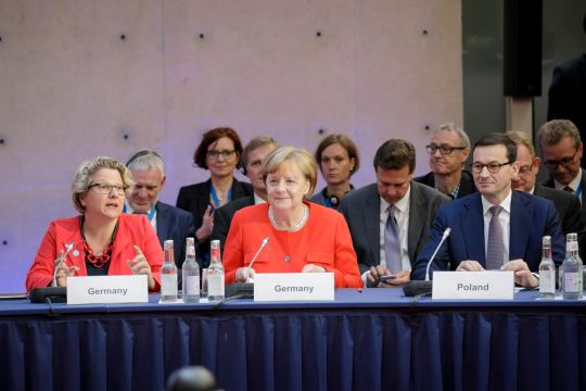 Umweltministerin Svenja Schulze (SPD), Bundeskanzlerin Angela Merkel (CDU) und der polnische Premierminister Mateusz Morawiecki (PiS), die gemensam an einem Verhandlungstisch sitzen. 