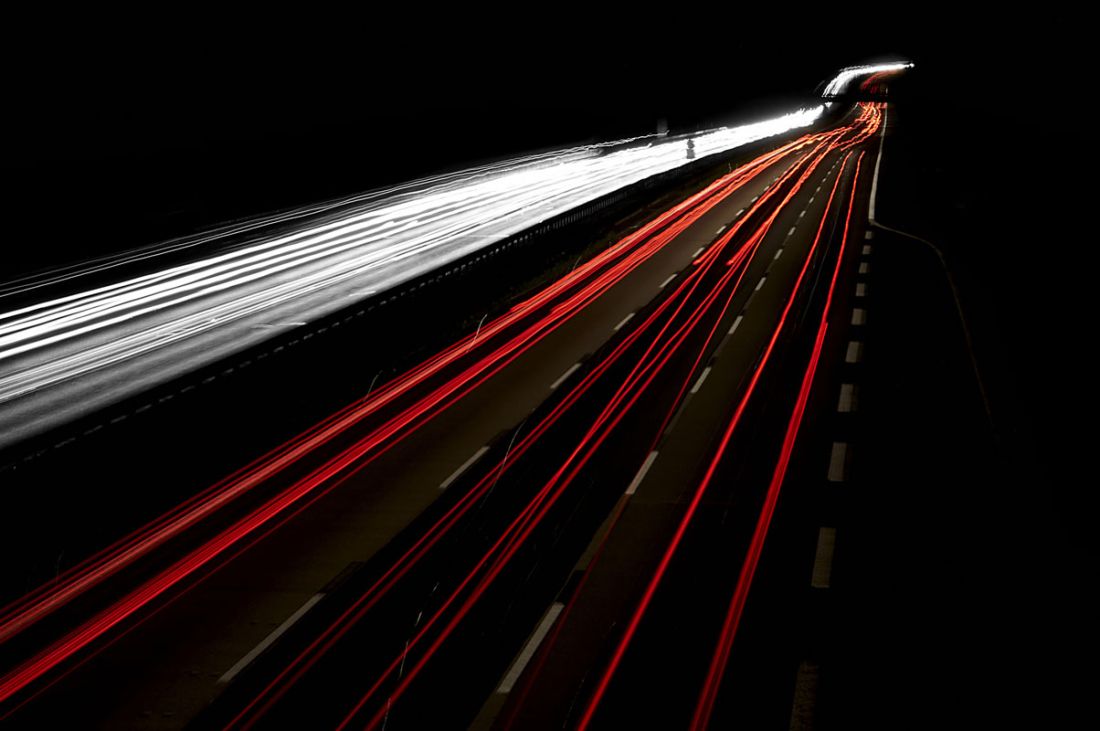 Autobahn in der Nacht: Rote und weiße Leuchtstreifen entstehen auf dem Foto.