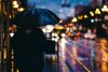 Ein Mensch mit einem Regenschirm geht neben einer Straße