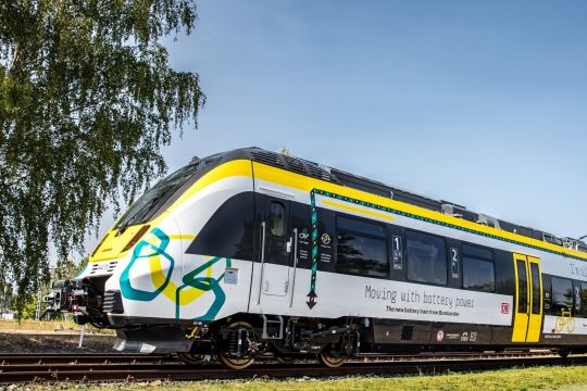 Ein weißer Regionalzug-Triebwagen mit gelber und türkisfarbener Bemalung und der Aufschrift: "Moving with battery power"