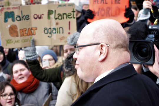 Peter Atlmaier vor einem Plakat mit der Aufschrift 