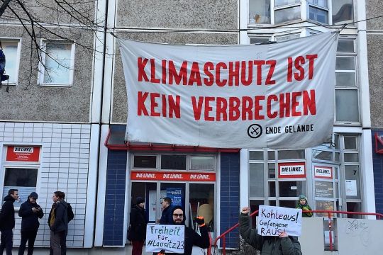 Vor einem Plattenbau hängt ein Transparent mit der Aufschrift Klimaschutz ist kein Verbrechen