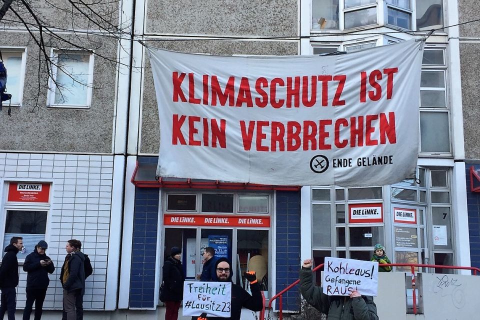 Vor einem Plattenbau hängt ein Transparent mit der Aufschrift Klimaschutz ist kein Verbrechen